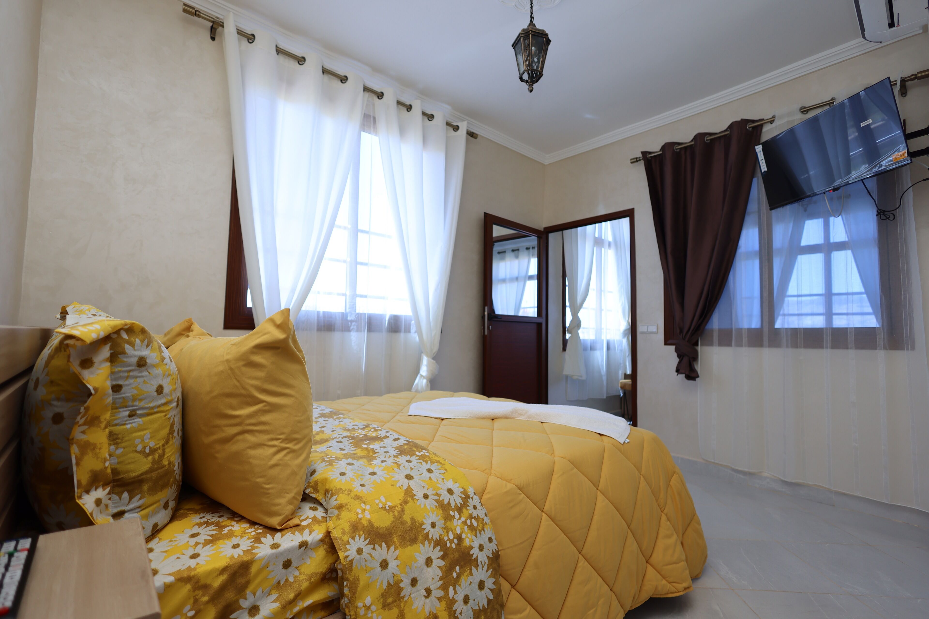 A bedroom with a bed, curtains, a television, and a door.