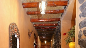 A narrow hallway with a red carpet, stone walls, and wooden beams. - Hotel palais d'orient (Tafoughalt)