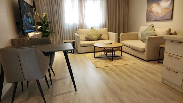 A modern living room with a sofa set, a coffee table, a TV, and a dining area. - ALWURUD ALARBA FOR SERVICED APARTMENTS (Riyadh)