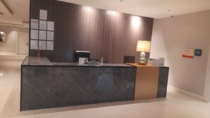 A reception desk with a dark marble top, a wooden panel wall, and a lamp. - ALWURUD ALARBA FOR SERVICED APARTMENTS (Riyadh)
