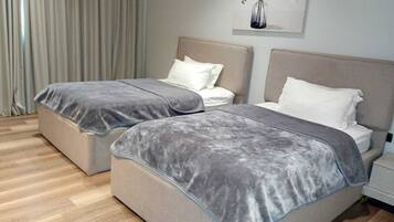 A hotel room with two beds, a nightstand, and a painting on the wall.