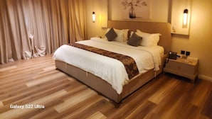 A spacious bedroom with a large bed, wooden flooring, and a nightstand with a lamp. - ALWURUD ALARBA FOR SERVICED APARTMENTS (Riyadh)