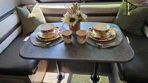 A cozy seating area with a table set for two, featuring floral tableware and a vase with dried flowers. - Tranquil Stay Close to Hotspotsin charming Medway (Medway)