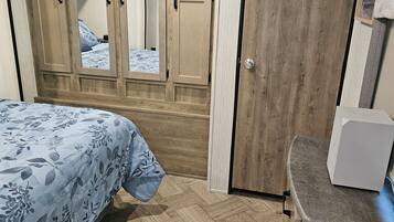 Ein Schlafzimmer mit einem Bett, einem Kleiderschrank, einem Spiegel und einer kleinen Küchenzeile.
