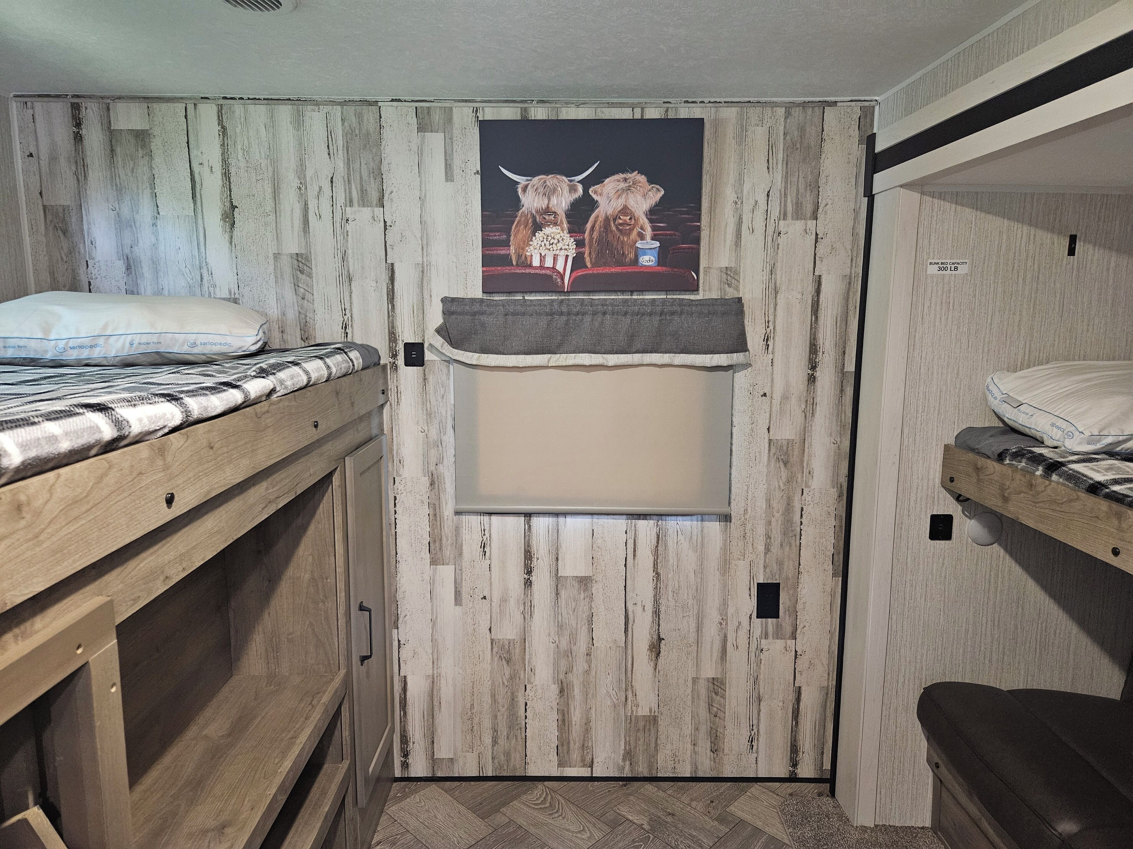 A bunk bed room with a wooden wall and a poster of two bulls.