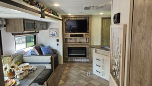 A compact RV interior with a kitchenette, a seating area, and a mounted TV. - Tranquil Stay Close to Hotspotsin charming Medway (Medway)