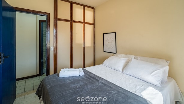 A hotel room with a bed, a blue door, a wooden partition, and a framed picture on the wall. - Apartment With Balcony and sea View - Ier0305 (Salvador)
