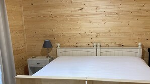 A wooden-paneled room with a bed, a nightstand, a lamp, and a rug. - Charming 1-bedroom studio in the mountains (Greeneville)