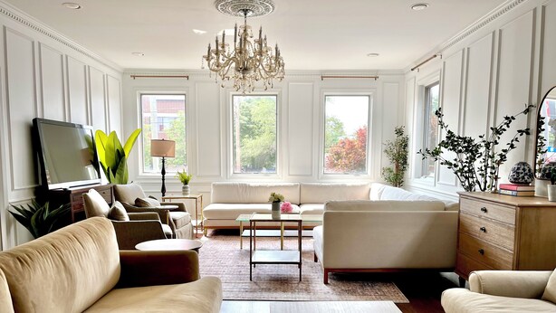 A spacious living room with a large chandelier, multiple seating options, and a chessboard on the floor. - 6 BDRM/ 6 BATH LUX Avondale Home, Sleeps 15, Rooftop Deck & 2 Car Garage! (Chicago)