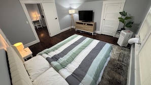 A bedroom with a bed, a TV, a dresser, and a plant. - Spacious Yale 2BR with Full Kitchen & WiFi (New Haven)