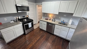 A modern kitchen with white cabinets, a stainless steel refrigerator, a microwave, a stove, and a dishwasher. - Spacious Yale 2BR with Full Kitchen & WiFi (New Haven)