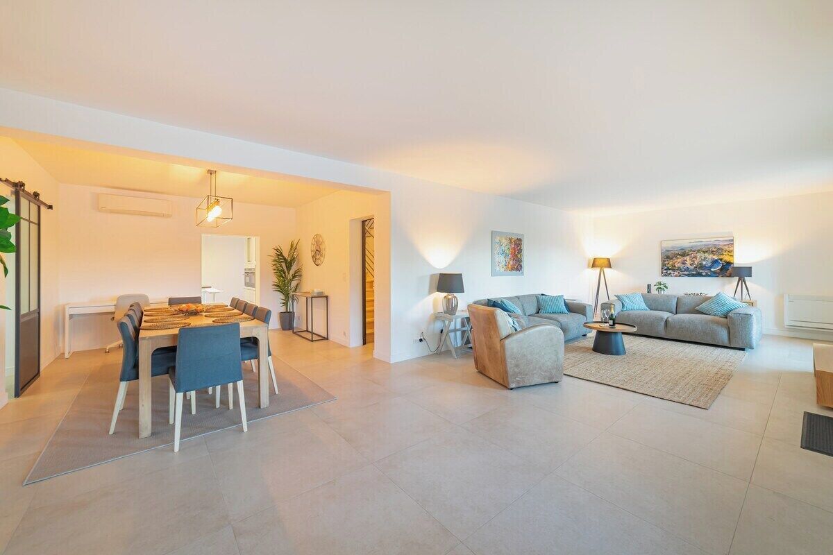 A modern living room with a sofa, a dining table with chairs, and a coffee table.