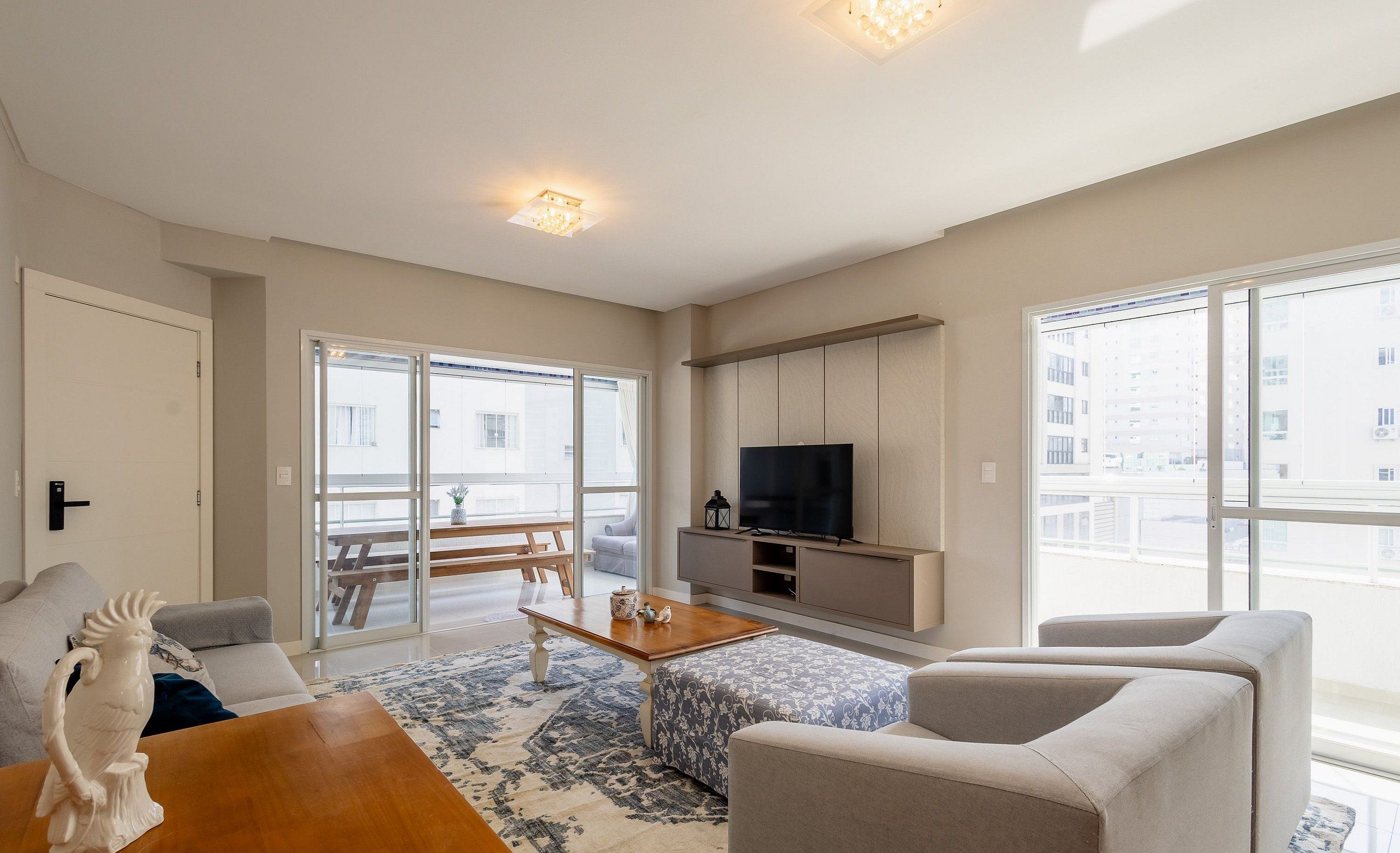 A modern living room with a sofa, a wooden coffee table, and a television on a stand.