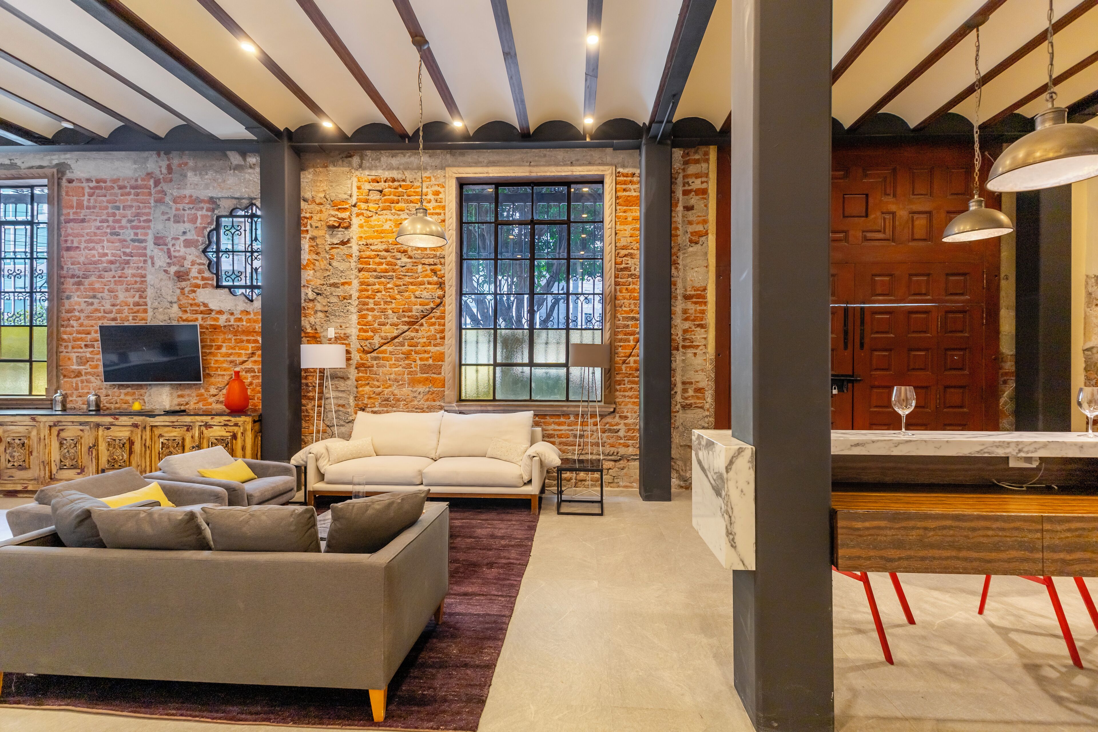 A living room with a sofa, a television, and a brick wall.