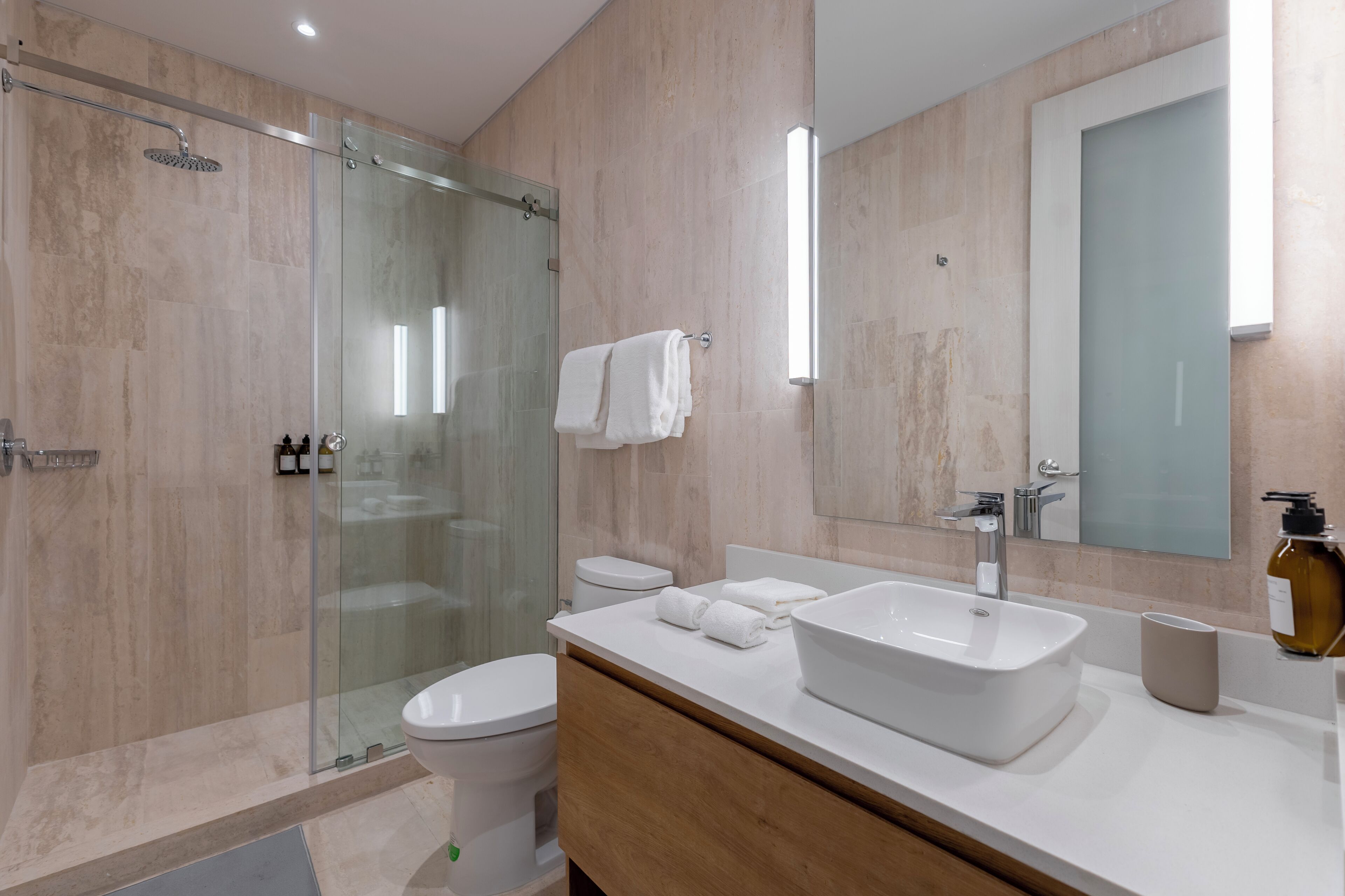 A modern bathroom with a glass shower enclosure, a white sink, and a large mirror.