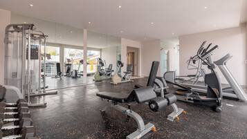 A gym with exercise equipment, a bench, and a mirrored wall.