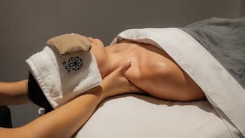 A person receiving a massage with a towel and a hand on their back.