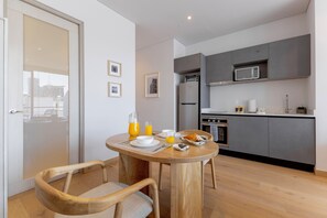A modern kitchen with grey cabinets, a microwave, and a stainless steel refrigerator. There is a dining table with chairs, a pitcher of orange juice, and a plate of food. - Capitalia Juarez (Mexico City)