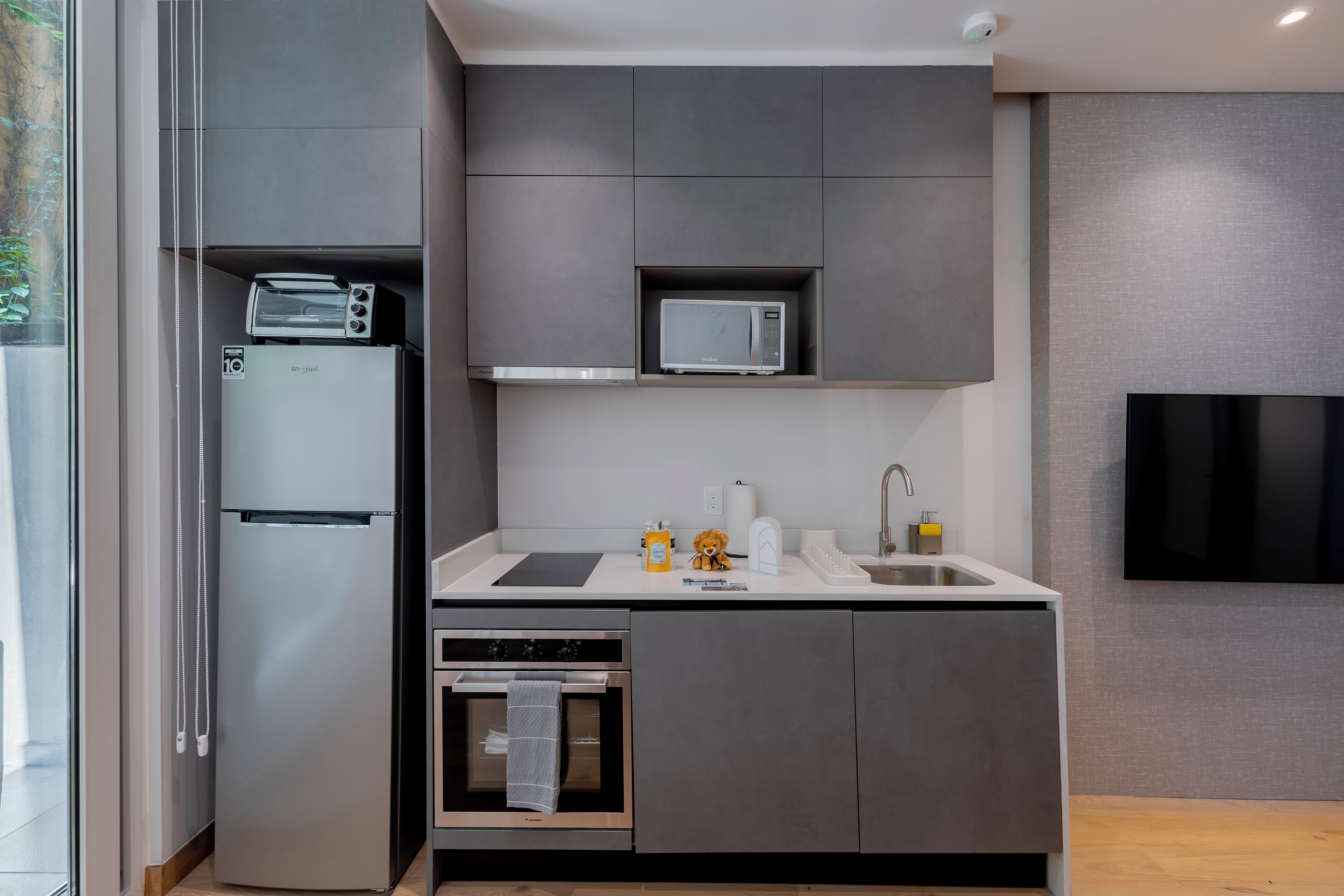 A modern kitchen with a built-in oven, microwave, and a small refrigerator.