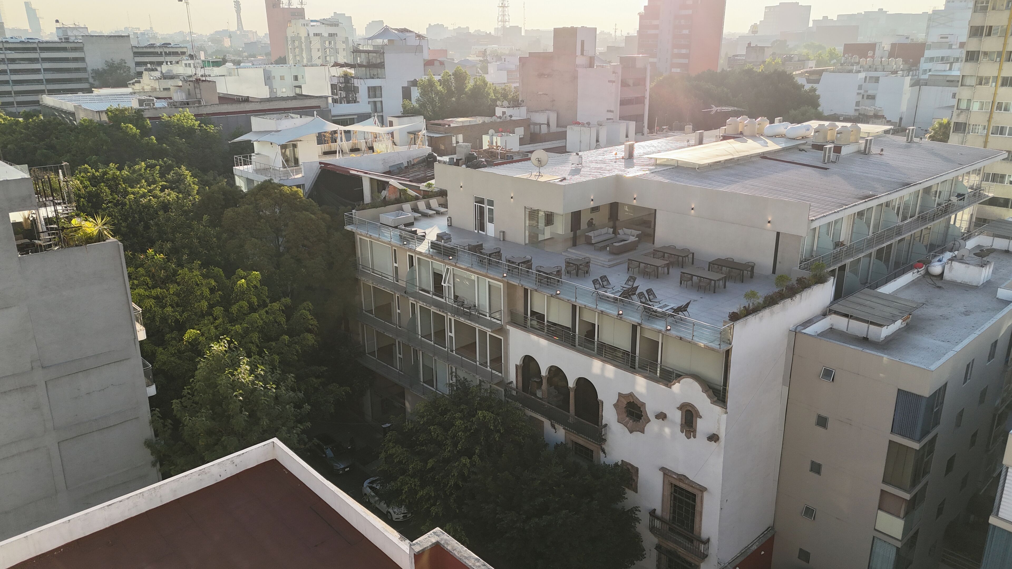 A multi-story building with a rooftop terrace featuring outdoor seating and a view of the cityscape.