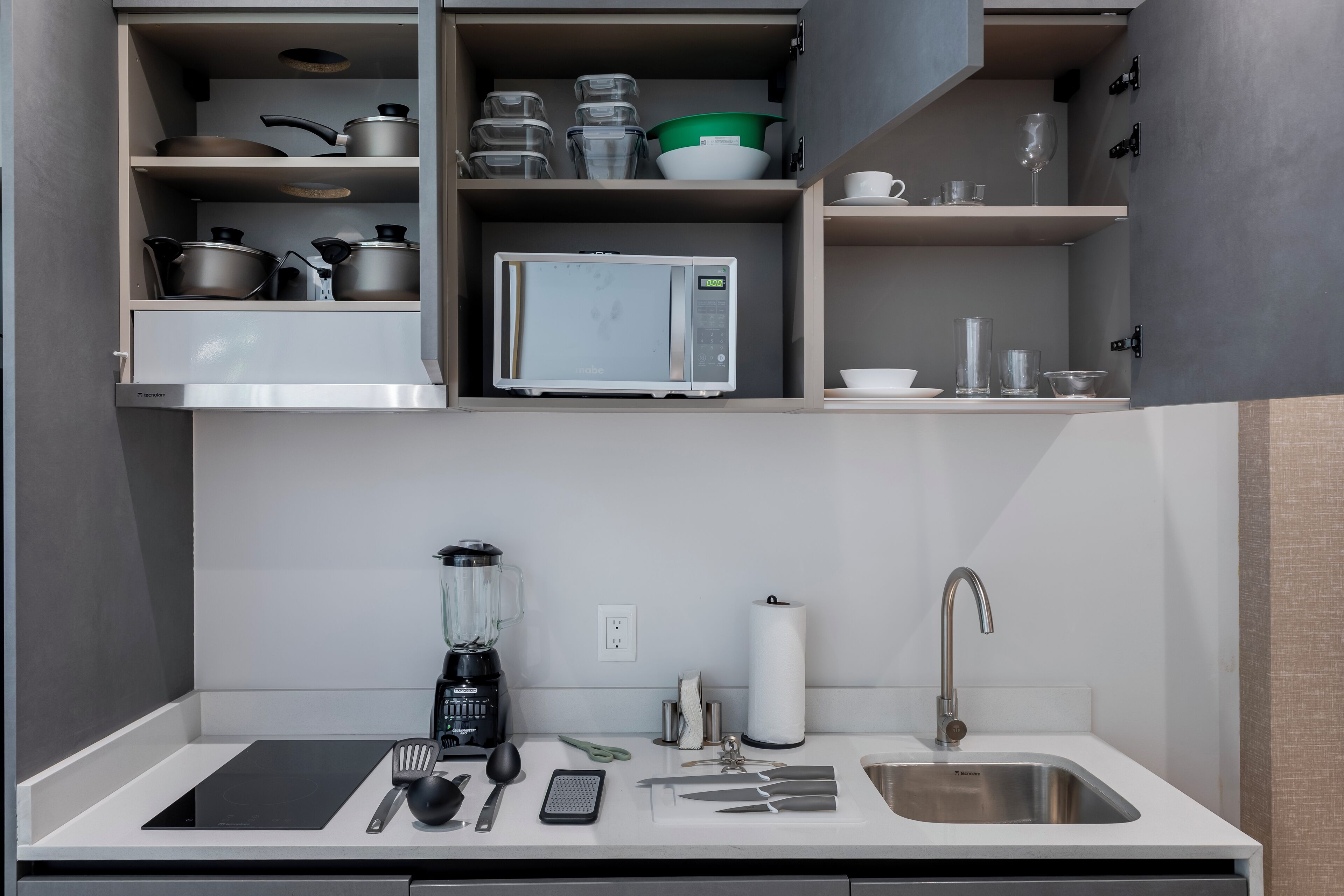 Une cuisine moderne équipée d’un four à micro-ondes encastré, d’une machine à café et d’un évier.