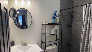 Ein modernes Badezimmer mit Waschbecken, Spiegel, Toilette und Duschbereich.