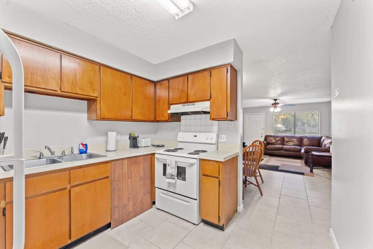 A kitchen with wooden cabinets, a white stove, and a sink.