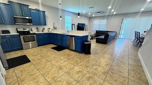 A spacious kitchen with blue cabinets, a stainless steel oven, and a dishwasher.