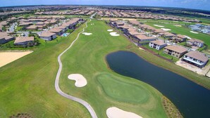 A golf course with a water hazard, sand bunkers, and a clubhouse.