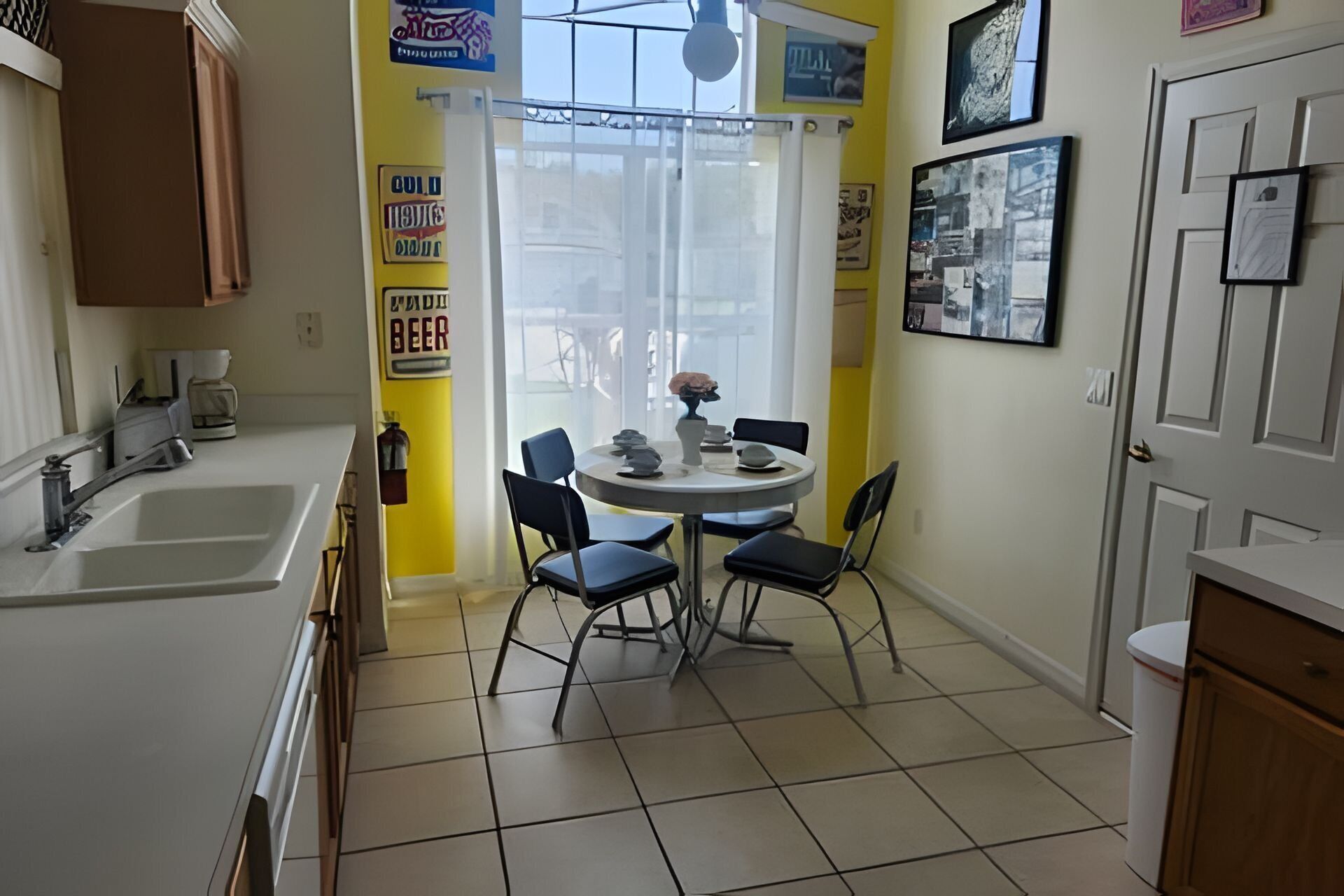 A small kitchen with a dining table, chairs, and a window with a view.