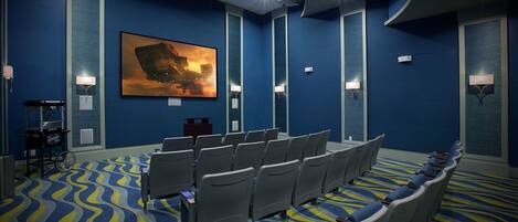 A conference room with rows of chairs, a large painting on the wall, and a patterned carpet.