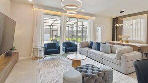 A modern living room with a sofa, chairs, a coffee table, and a TV.