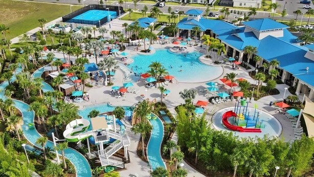 An aerial view of a resort with multiple swimming pools, water slides, and lounge areas surrounded by palm trees.