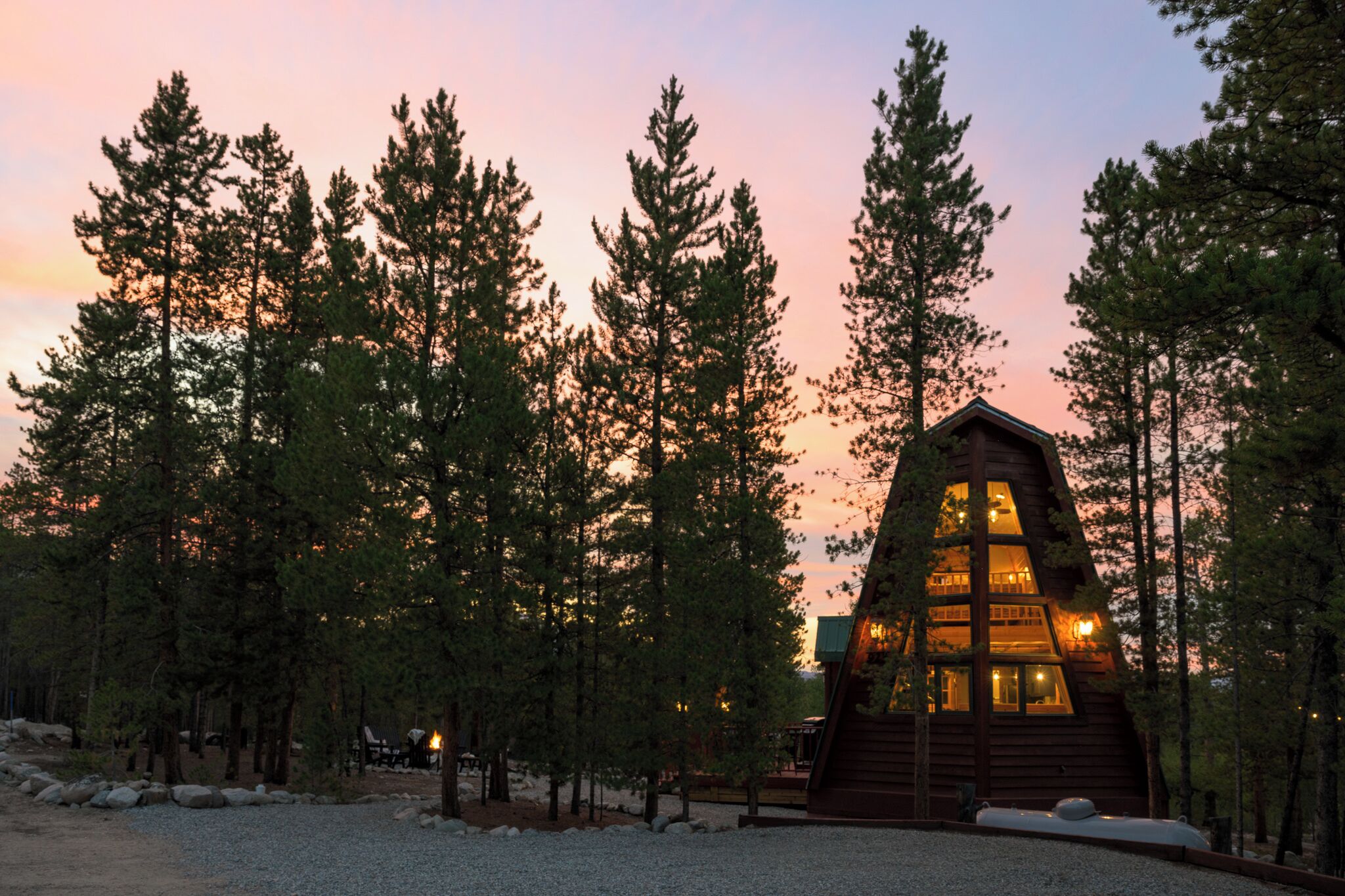 A cabin with a triangular roof surrounded by tall pine trees.