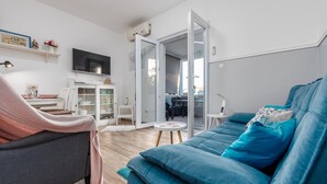 A modern living room with a grey sofa, teal cushions, a white cabinet, and a flat-screen TV. - Beautiful apartment in Preko with house sea view (Preko)