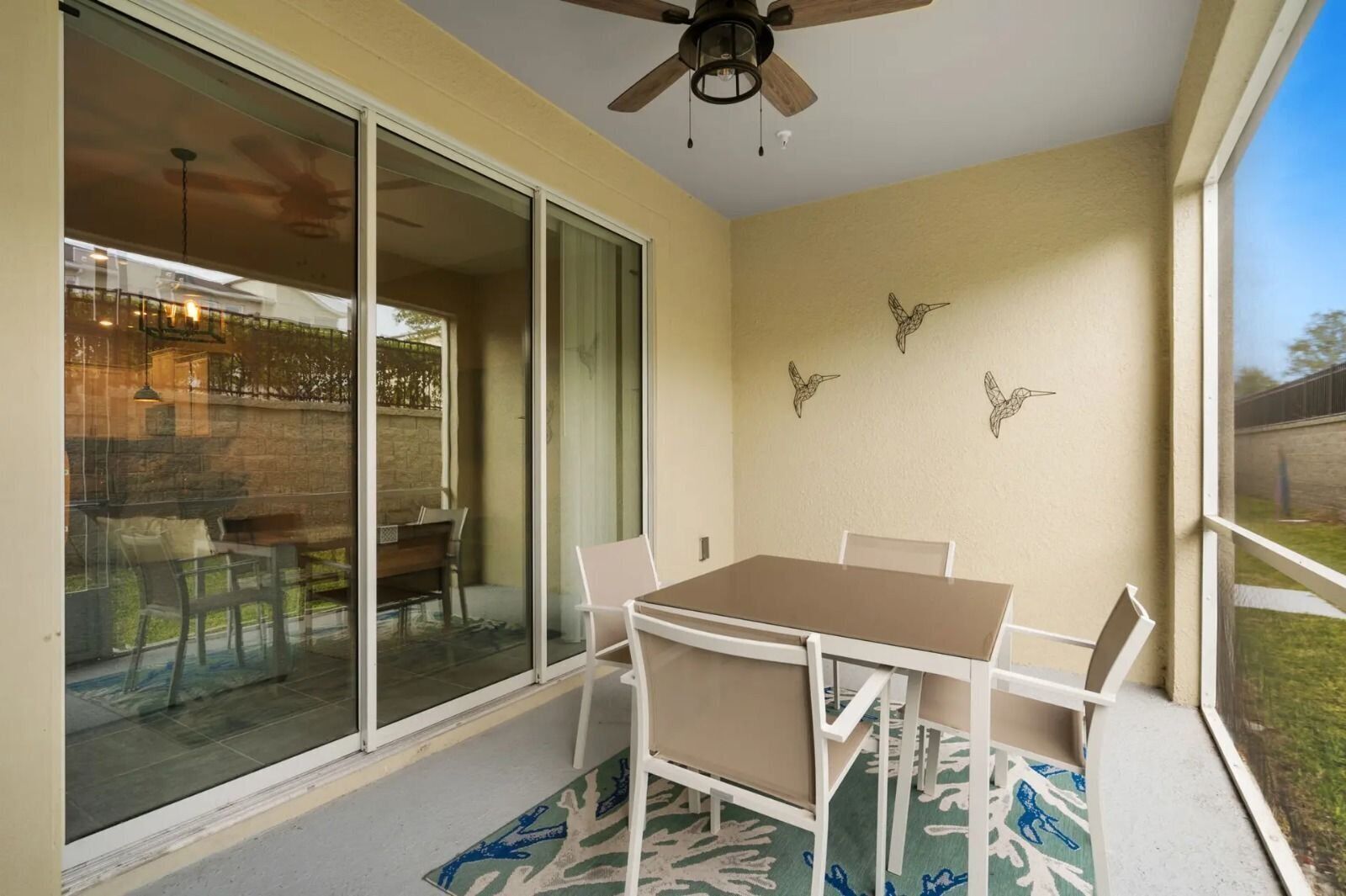 A patio with a table and chairs, a ceiling fan, and a view of the backyard.