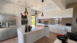 Una cocina moderna con armarios blancos, una isla central e iluminación colgante.