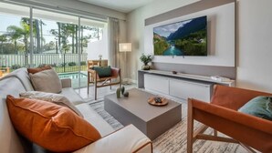 Un salon moderne avec un canapé, une table basse et un téléviseur fixé au mur.