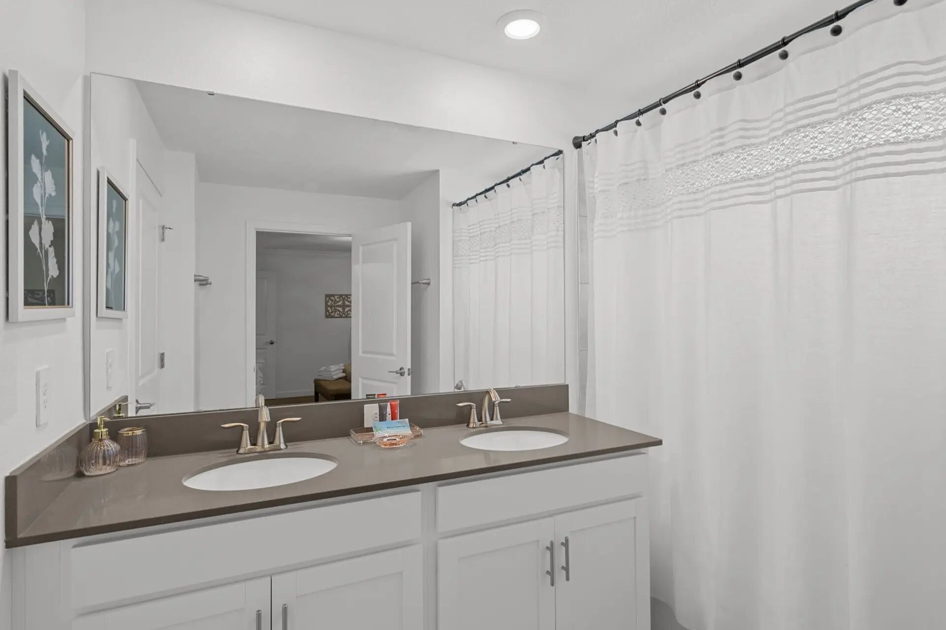 A bathroom with a double sink vanity, a large mirror, and a shower curtain.