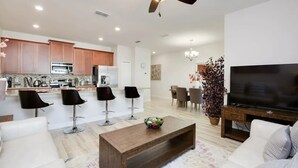 A modern living room with a wooden coffee table, a TV, and a ceiling fan.