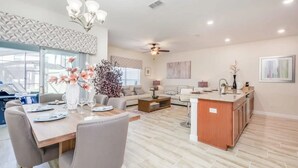A spacious living area with a dining table, sofas, and a kitchen island.
