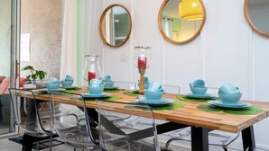 A dining area with a wooden table, clear chairs, and blue tableware.