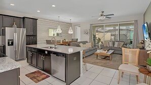 A modern kitchen with a central island, built-in appliances, and a dining area with a sofa and coffee table.