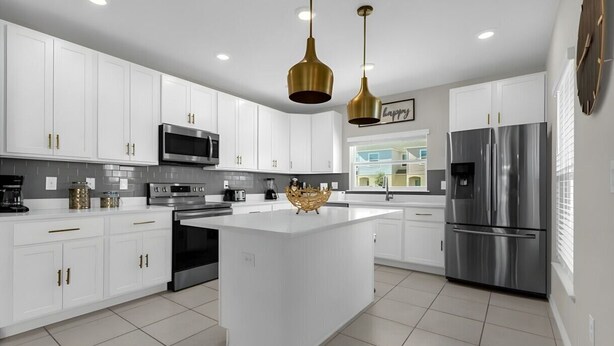A modern kitchen with white cabinets, stainless steel appliances, and a central island. - Cozy 3BR Home Near Disney & Outlets (Kissimmee)
