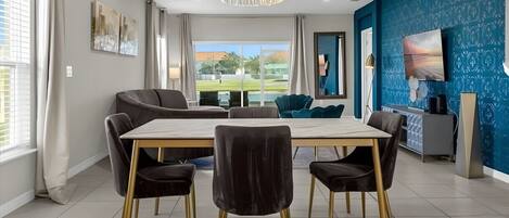 A modern dining area with a marble table, black upholstered chairs, and a chandelier.