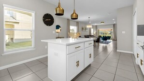 A modern kitchen with white cabinetry, gold handles, and pendant lighting. - Cozy 3BR Home Near Disney & Outlets (Kissimmee)