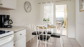 A compact kitchen with a coffee maker, a clock, and a dining area with chairs and a table. - Beautiful Retreat *5min -> Disney *Pool *King Bed (Kissimmee)