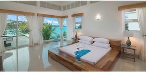 Um quarto espaçoso com uma cama grande, vista para o oceano e uma varanda.