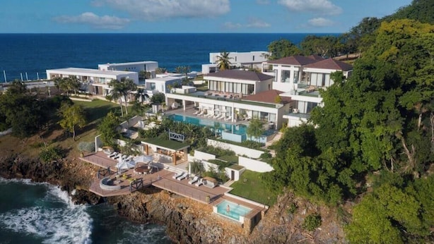 Um imóvel costeiro com piscina, vários edifícios e vista para o mar.