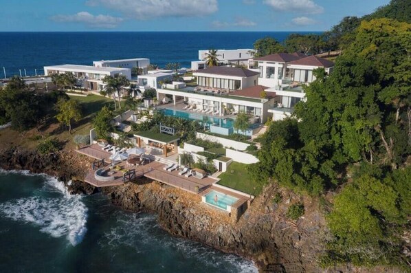 A coastal property with a pool, multiple buildings, and a view of the ocean.